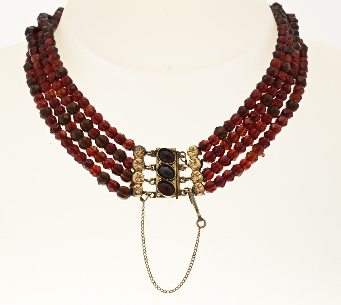 Gold garnet necklace with gold clasp: Necklace with 4 rows of garnet stones, ø4.3 mm., attached to a yellow gold clasp, 585/000, with garnet stones and end pieces. Width 18 mm. Length 33 cm. Total approx. 29.9 grams. Fitted with a base