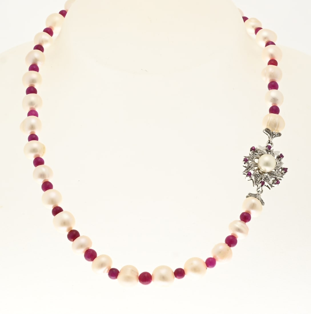 Pearl and garnet necklace with white gold clasp: Necklace with freshwater pearls and almandine beads, attached to a white gold clasp, rosette decorated with a pearl and a border with small rubies. ø 18 mm. Length 44 cm. In good condition.