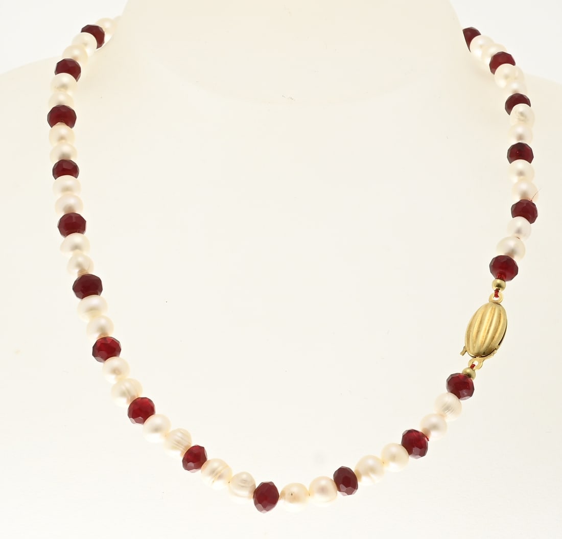 Pearl and garnet necklace with gold clasp: Necklace of freshwater pearls and faceted garnets, ø 6-6.5 mm, 2 by 1, attached to a yellow gold almond-shaped clasp, 585/000, with ribbed decoration. 8x4x18mm. Length 40 cm. In very good condition.