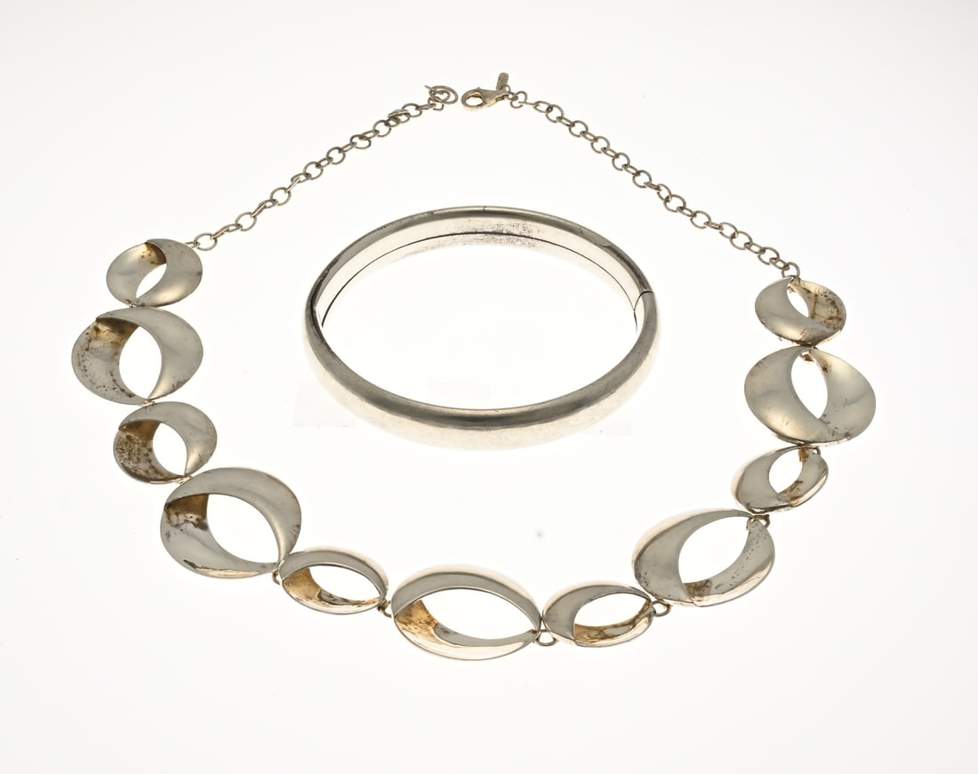 Silver necklace and bracelet: Silver fantasy necklace, 925/000, and a bangle, 835/000. Necklace with small and large round elements, ø18-26mm., with anchor chain on both sides. And a bangle with a cap clasp, a small dent on the