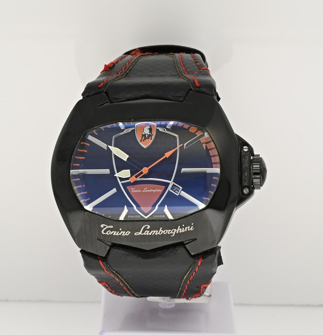 Lamborghini watch: Large Tonino Lamborghini, quartz, with a black ionized contoured case with red details on the dial. The watch has a leather strap with a tear and a clip clasp. Case width 61 mm. Working. In good