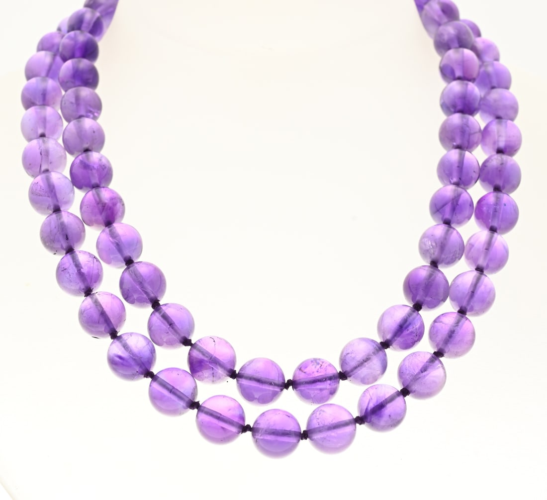 Amethyst bead necklace: Long necklace of round amethyst beads, ø 10 mm, knotted on a gold-on-silver ball clasp with amethyst. Approx. 84 cm. In good condition.