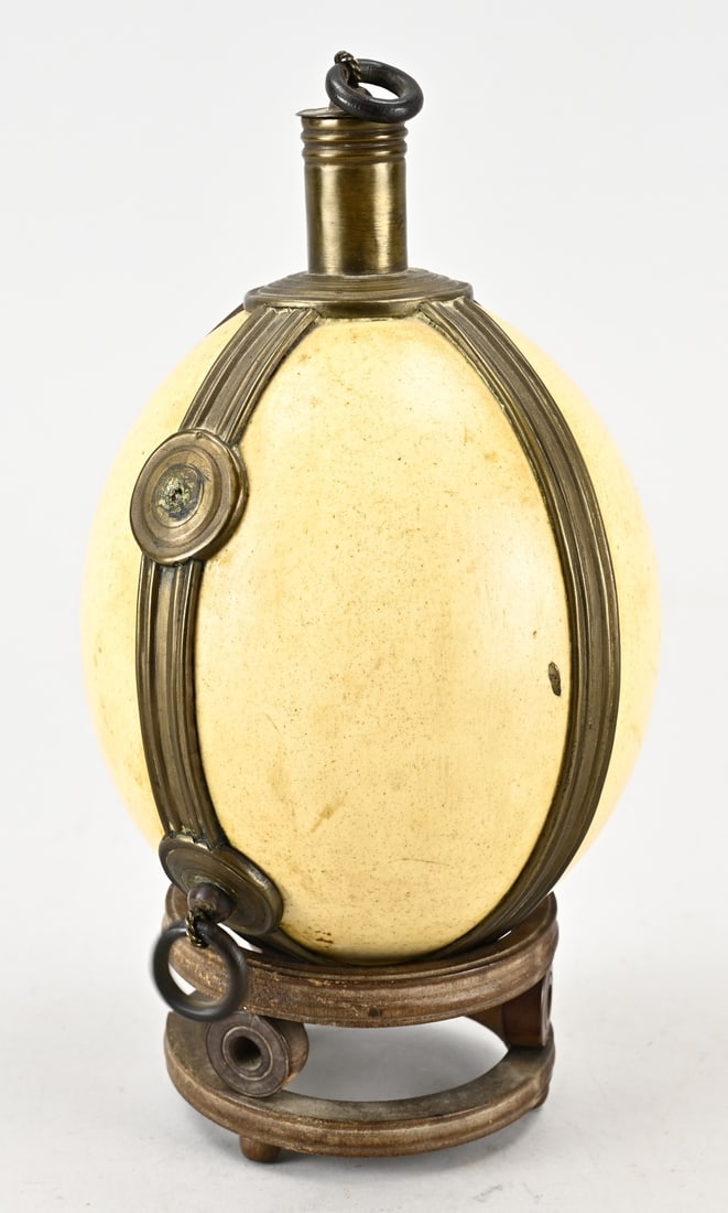 Ostrich egg (herb holder): Antique ostrich egg as a spice holder, with a brass mount, placed on a wooden (Oriental) console. Dimensions: 24 cm. In good condition.