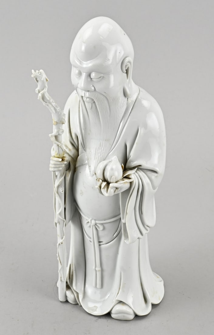 Blanc de chine statue, H 32.5 cm.: Antique Chinese porcelain blanc de chine statue, deity with peach. Dimensions: H 32.5 cm. Staff glued. In reasonable condition.