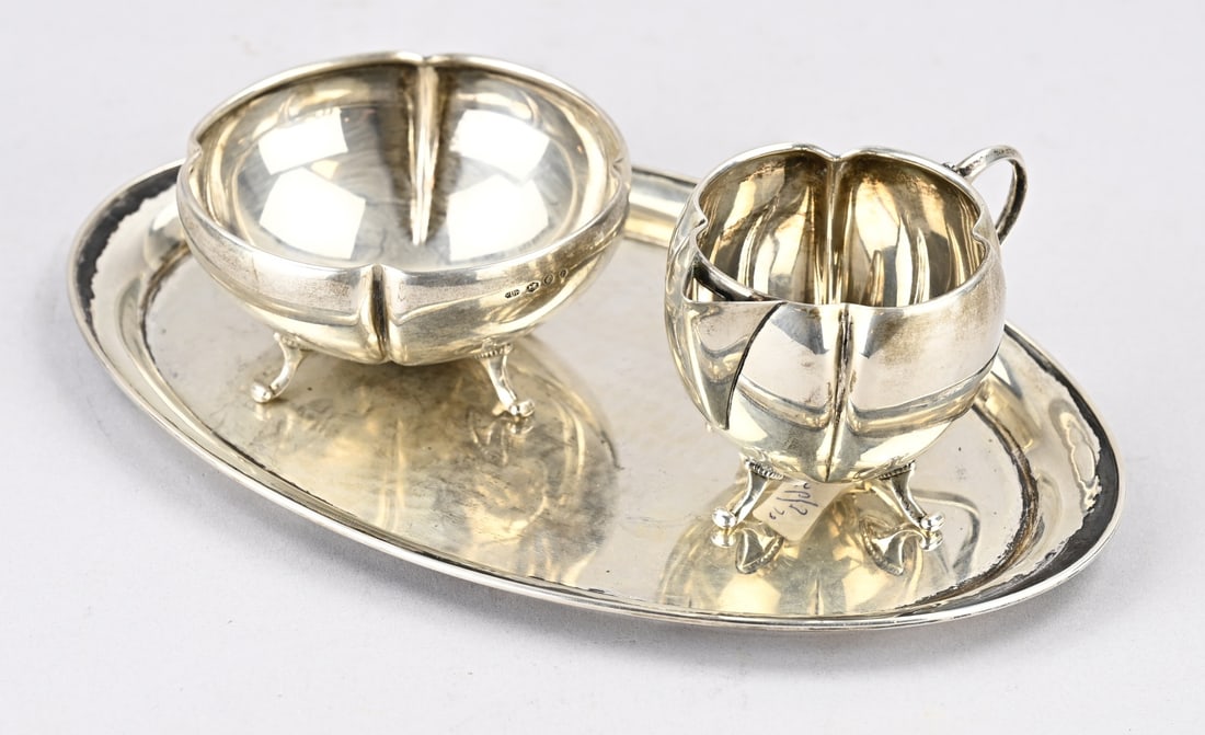 Silver cream set, 3-piece: Silver cream set, 833/000, 3-piece, pumpkin-shaped milk jug and sugar bowl on 4 curled feet. Placed on an oval serving tray with a rim. MT.: H.Hooijkaas, Schoonhoven, year: NO, 1948-1949. 11x7x6.5cm