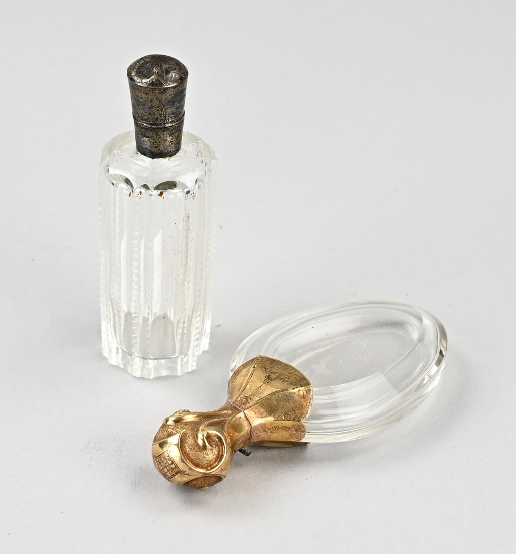 2 Fragrance bottles, gold and silver: Two crystal perfume bottles, a horizontal pear-shaped bottle with a yellow gold collar and cap, 585/000, 10x4.5cm, and a cylindrical cut bottle with a silver collar and cap, 833/000, with trembled