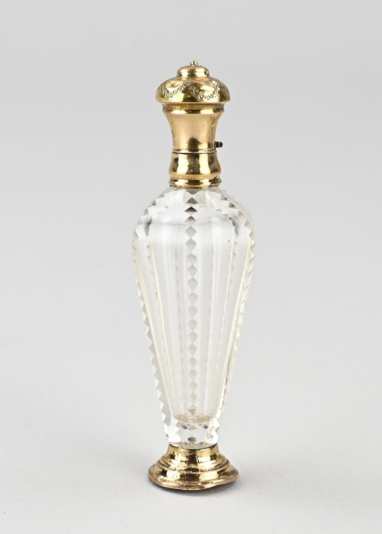 Fragrance bottle with gold: Crystal perfume bottle with gold, 585/000. Bottle on a round yellow gold base, a gold collar and cap in the shape of a flower bud. Slightly out of shape and dented. Fitted with an inner stopper. 10.5