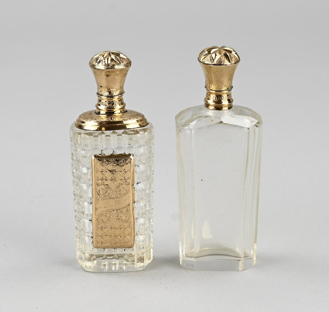 2 perfume bottles with gold: Two crystal perfume bottles with gold, 585/000. Rectangular contoured bottle with a yellow gold shield with engraving and a large gold collar and cap. 9x3x2cm. Slightly crooked. And a rectangular