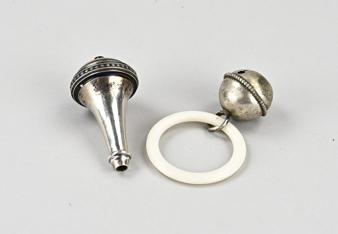 Silver rattle and bell: Lot with a silver rattle and bell, 835/000. Plastic ring with a small silver ball with a beaded rim attached, ø 28 mm. Out of shape. And the handle of a silver bell, trumpet-shaped with an