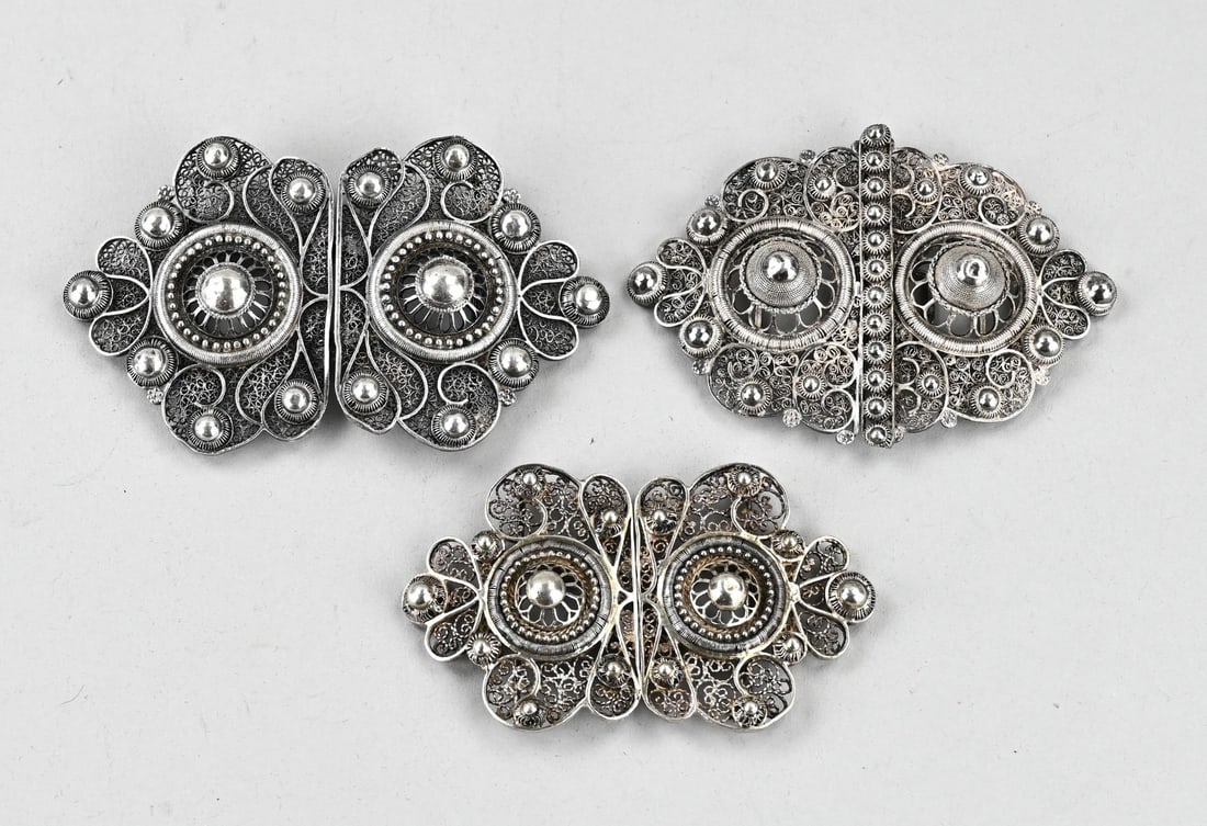 3 Silver belt buckles: Three silver belt buckles, 833/000, contoured models decorated with buttons and made of filigree. Total approx. 135 grams. 9-11cm. Small dents in the button, otherwise in good condition.