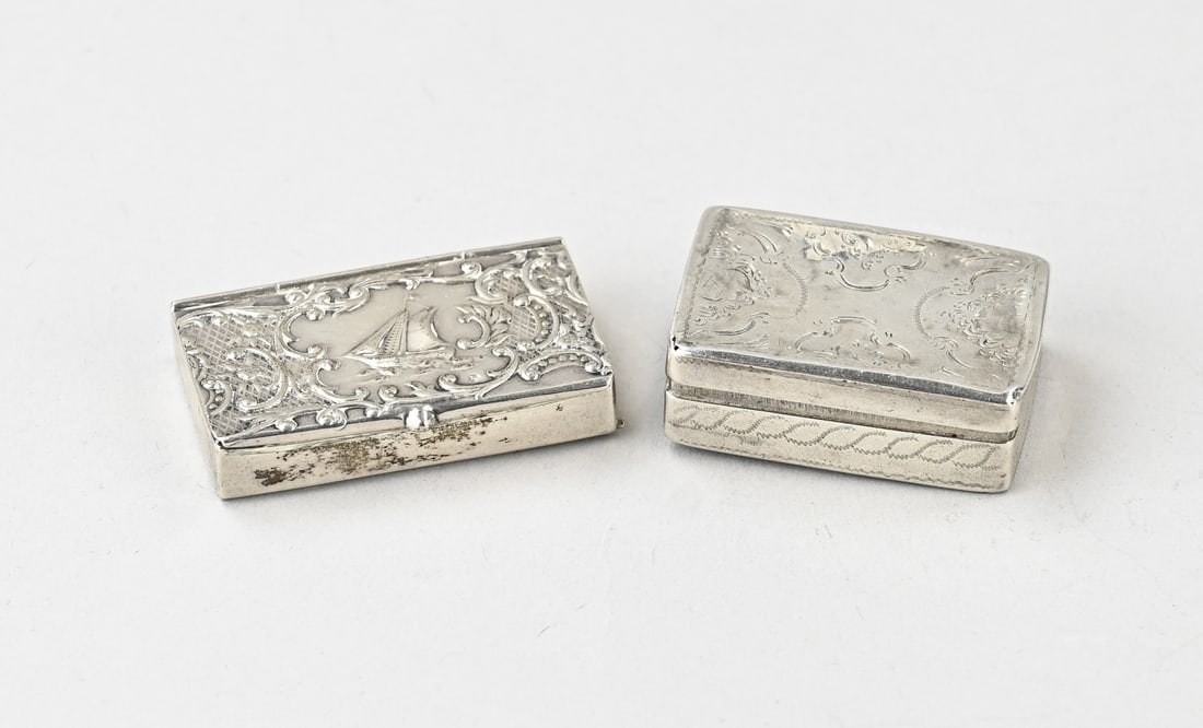Silver vinaigrette and silver pillbox: Lot with 2 small silver boxes, 833/000, with a rectangular vinaigrette decorated with engraving, dented. MT.: Unclear, dated:1868. 30x42x14mm. And a rectangular pillbox, 2 compartments, with a hinged