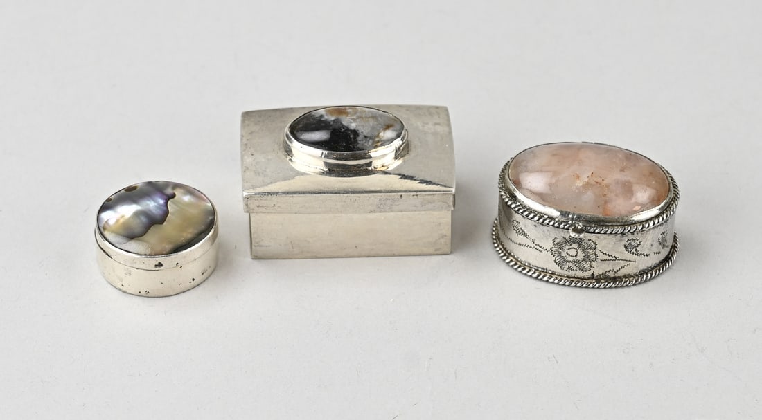 3 Silver boxes with gemstones: Three small silver boxes: a small round box with mother-of-pearl inlay in the lid, ø 25 mm. An oval box with a hinged lid set with a rose quartz and featuring a twisted rim. 4x3cm. Decorated