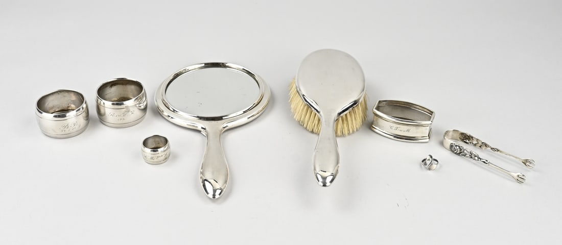 Silver brush set & napkin rings: Lot of silver with a silver brush set, featuring a smooth brush and a mirror, 925/000, MT.: Koninklijke van Kempen en Begeer, Voorschoten. jl.:p:1975. 3 silver napkin bands, a finger towel band, with