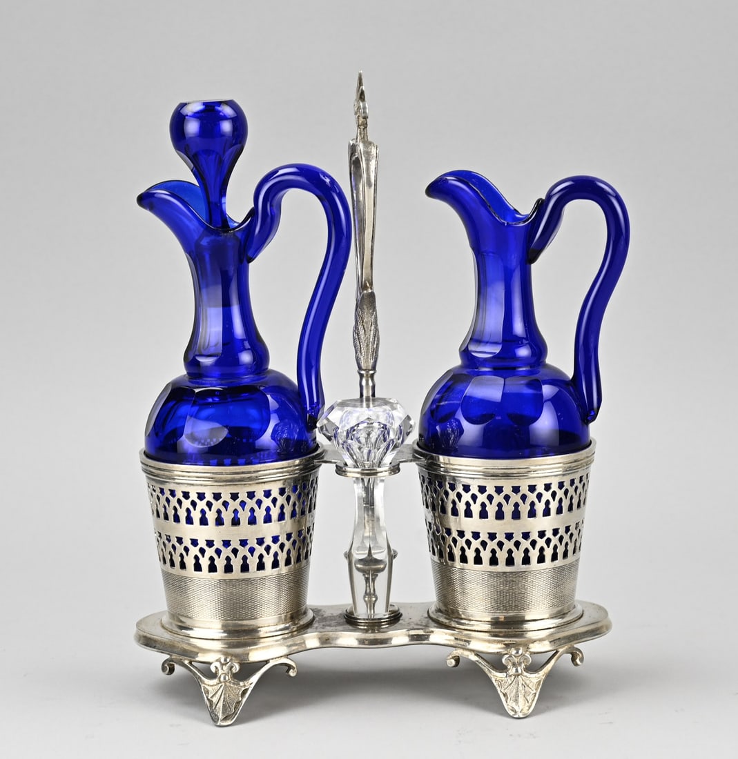 Oil and vinegar set, 1900: Antique oil and vinegar set in a plated holder. With blue glass carafes, one blue stopper replaced. Dimensions: 26 x 20 x 10 cm. In fair/good condition.