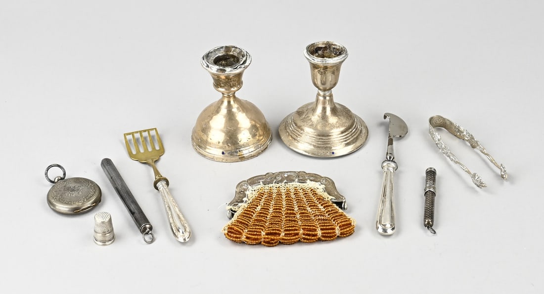 Lot of various silver: Lot of miscellaneous silver with 2 candlesticks, 2 pencil holders with niello, a clasp, thimble, sugar tongs, pocket watch, and a citrus knife and scoop with silver handles. Various finenesses. Gross