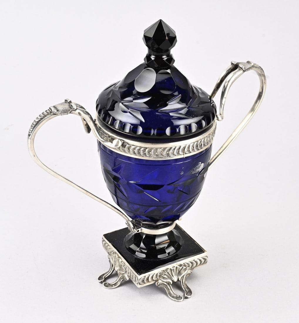 Silver goblet with blue glass: Blue glass goblet with silver, 833/000, Blue glass goblet with cut work placed on a square silver base with palmettes. And a silver mount with 2 handles and semi-circular decoration and curls. The