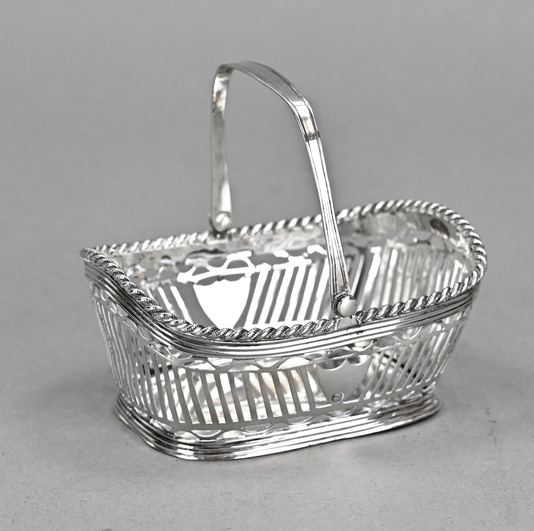 Silver bonbon basket, rectangular.: Silver bonbon basket, 833/000, rectangular sawed model with bars and semicircles and a bracket with line decoration. The rim features a twisted finish. MT.: H. van Delden & Zonen, Zwolle, 1920.