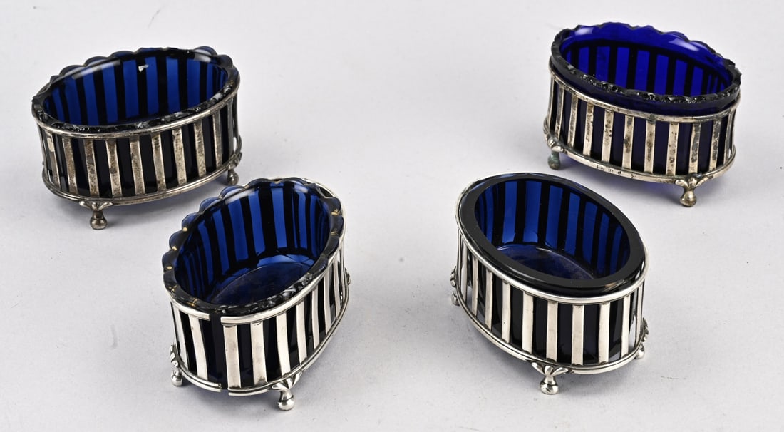 4 Silver salt cellars with blue glass: Four spice bowls with silver holders and blue glass inner bowls. Oval bowls decorated with a spindle motif and placed on ornate ball feet. With blue glass inner bowls. Models vary slightly. The rim