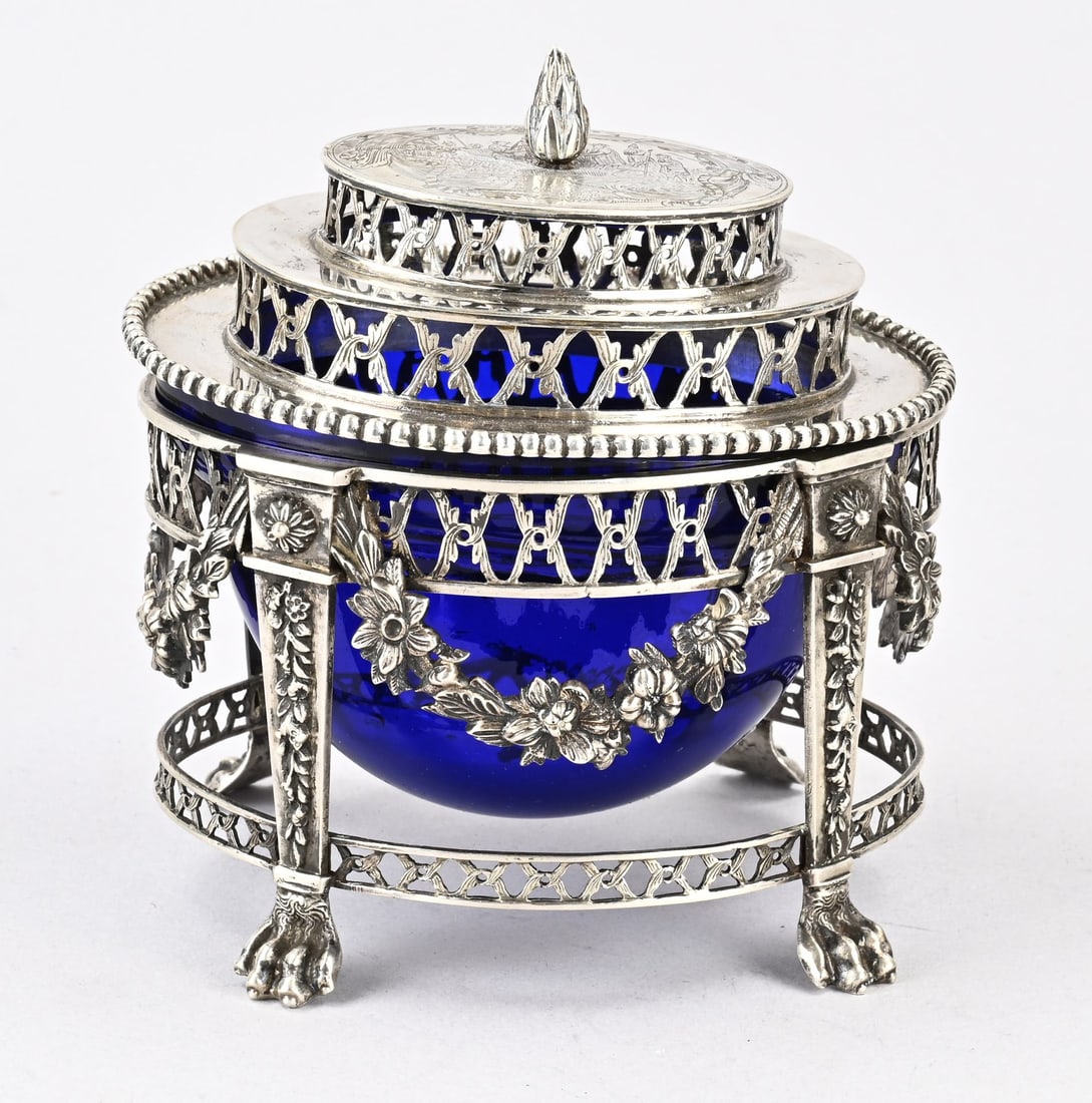 Silver bonbon dish: Silver bonbon dish with blue glass liner. 833/000, oval silver holder mounted on 4 claw feet with floral decoration and rosettes. The dish is decorated with garlands and sawed edges. The oval lid