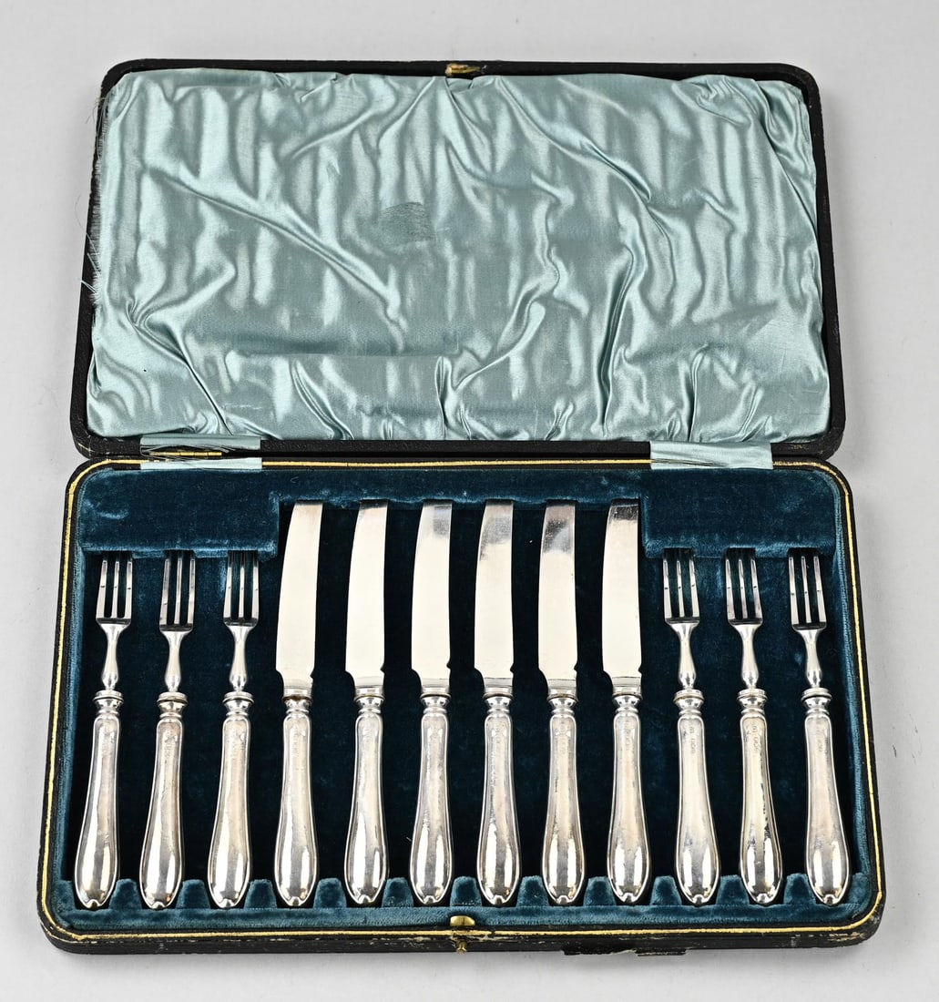 Cassette with 6 fruit knives and forks with silver handles: Cassette of fruit cutlery with silver handles, 925/000. 6 knives and forks with handles featuring a filigree edge with a decorative picket. MT.: Yates Brothers, Sheffield, dated: 1922. 16.5-18.5 cm.
