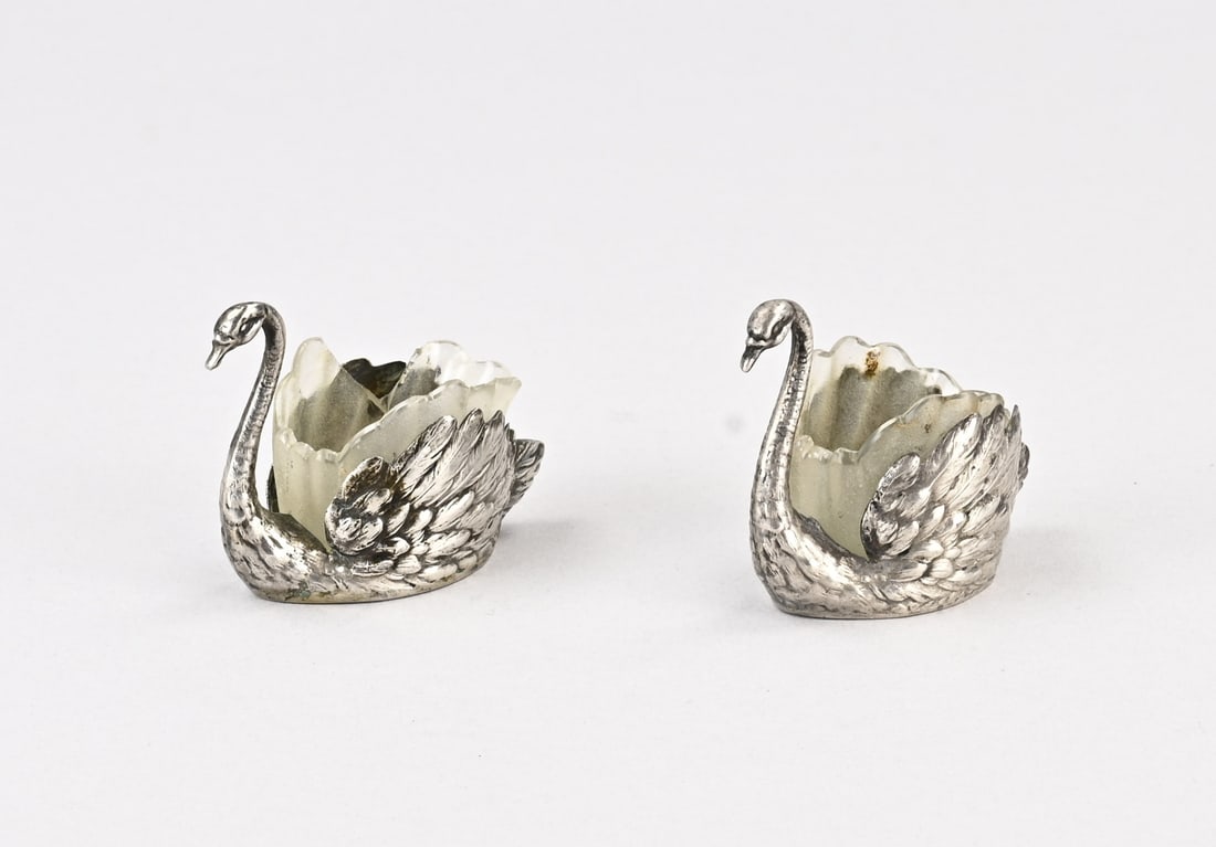 2 Silver Swans: Two silver spice bowls, 800/000, in the shape of a swan with a glass inner bowl. One with a chip. Gross weight approx. 59.7 grams. 6x3x5cm. In reasonably good condition.