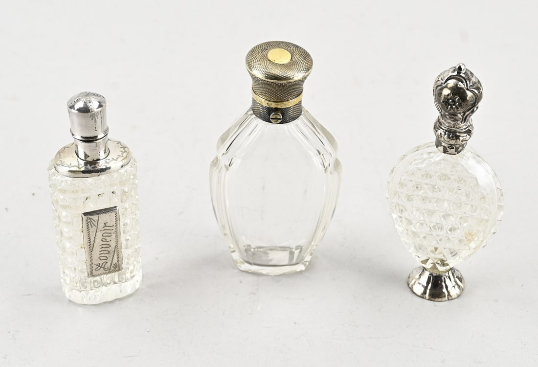 3 Fragrance bottles with silver: Three perfume bottles with silver, 833/000, various models decorated with cutwork, one with a silver element on the body and one on a silver base. 9-10 cm. In good condition.