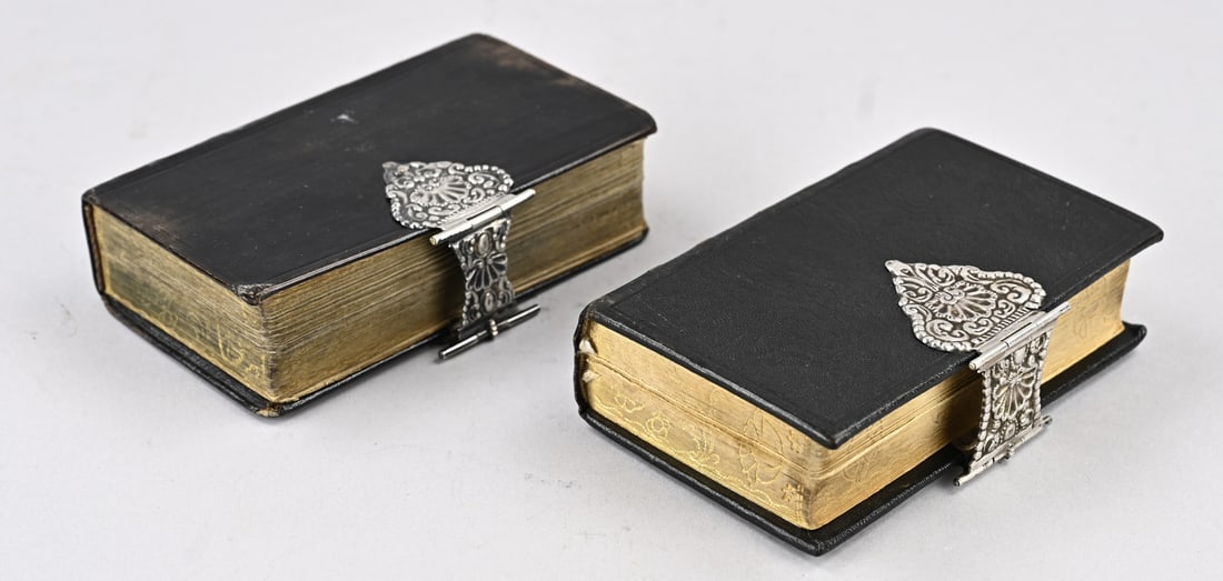 2 Bibles with silver clasps: Two Bibles with silver clasps, 833/000, the New Testament, with ornate leather covers and a silver clasp decorated with palmettes, scrolls, and a pearl border. 15.5x9x4cm. In good condition.