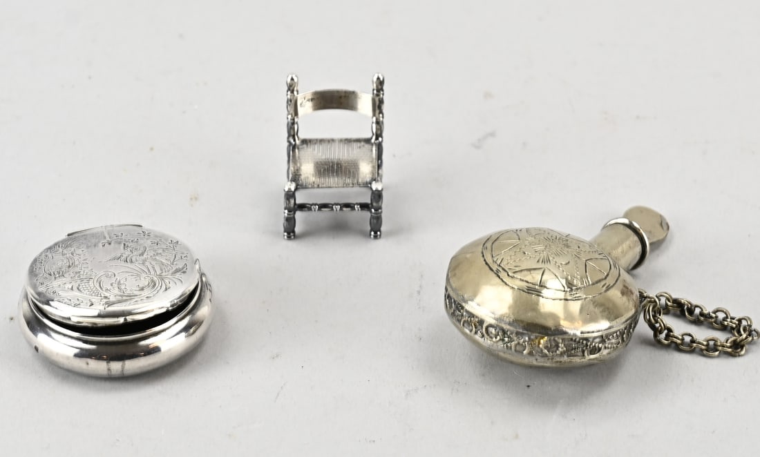 Box, flask and chair, miniature: Lot with a silver pillbox and a silver knob chair. And an antique white metal perfume bottle decorated with engraving. Presumably Navajo, Indian, or Moroccan.