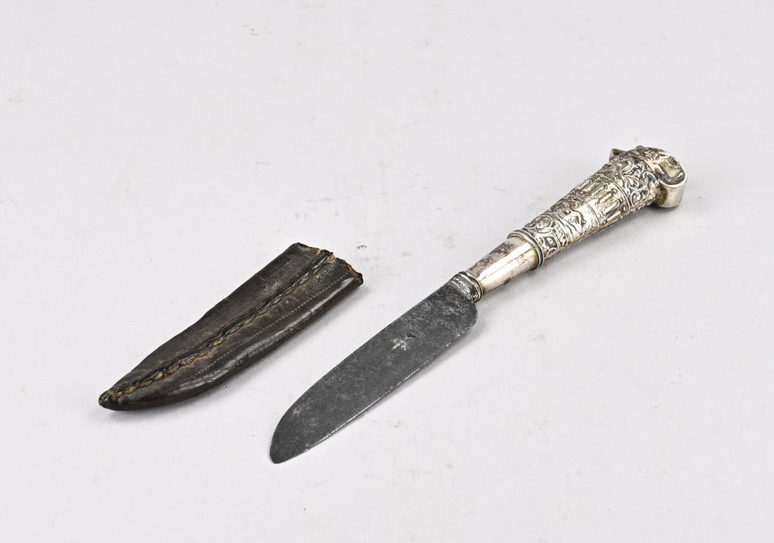 Traveling knife in leather sheath: Antique travel knife in a leather sheath. The knife features a silver pistol grip with floral decoration and dogs. The handle is crowned with a dog. MT.: JHHackenberg, Middelburg, 1843-1868. 20 cm.