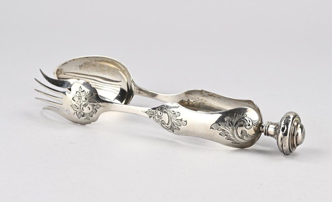 Silver salad tongs: Silver salad tongs, 833/000, with contoured handle decorated with floral engraving. Mt.: Unclear, date: e:1864. 26 cm. approx. 106 grams. The knob of the tongs is slightly dented and has a small