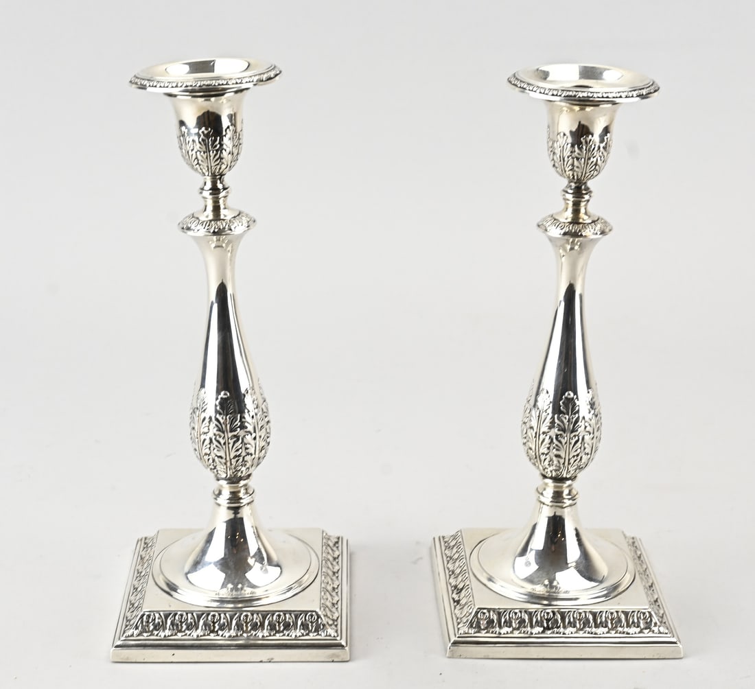2 Silver candlesticks: Two English silver candlesticks, 925/000, on a square base, with a pear-shaped baluster and a round light, all richly decorated with acanthus leaves. On one candlestick, the light is slightly askew, t