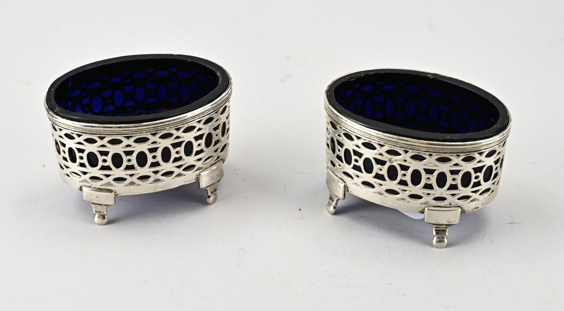 2 Silver salt cellars with blue glass.: Two oval spice bowls with silver holders and blue glass. Oval bowl with sawed decoration featuring a circle, oval, and marquise-shaped decoration. Mounted on 4 feet with ball elements. 8x5.5x5cm.