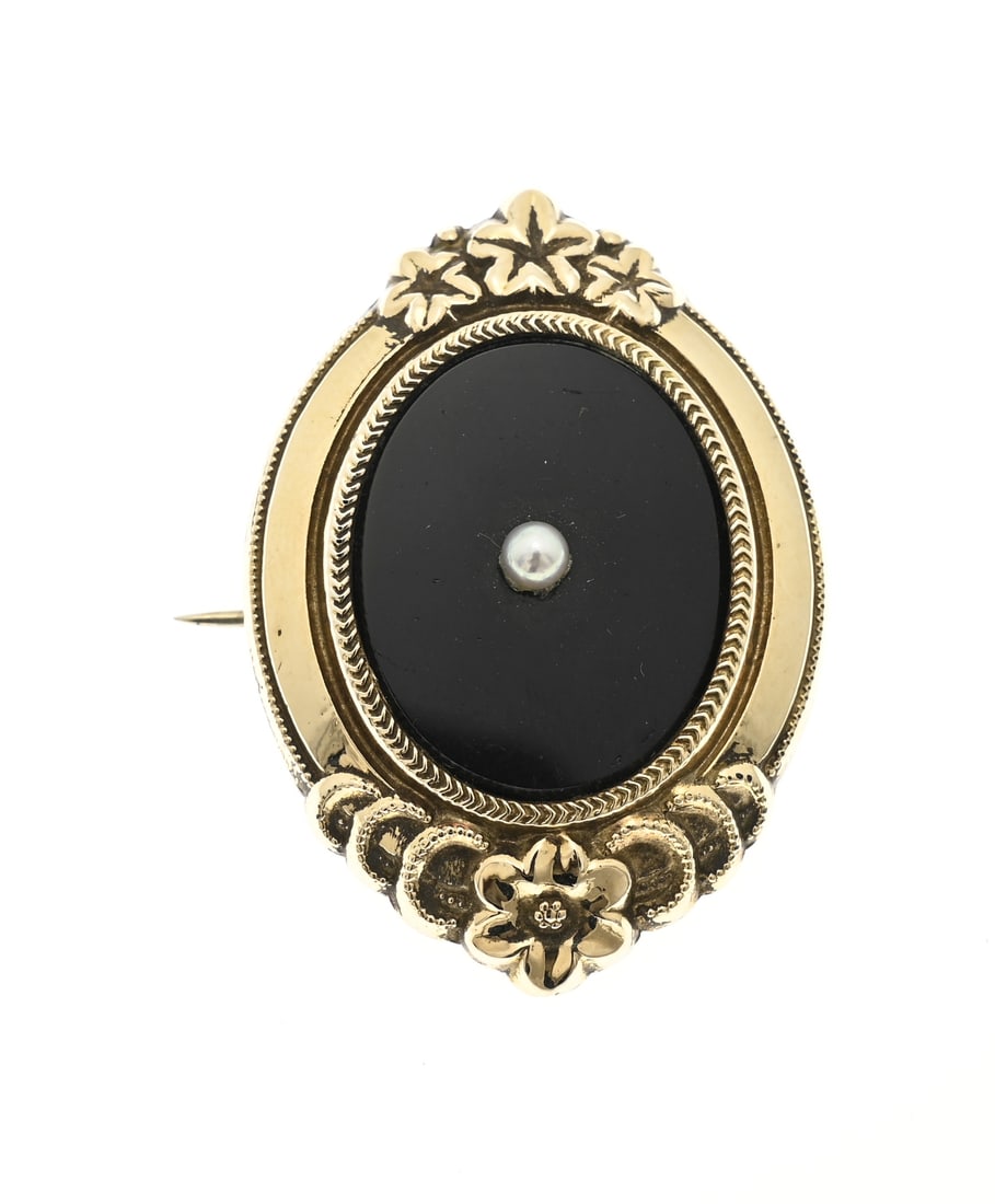 Gold, silver, and onyx brooch: Beautiful shield brooch, silver with gold, oval design with floral elements at the top and bottom, an oval decorated border with an onyx. A pearl is set in the center of the onyx. 45x29mm. Approx.
