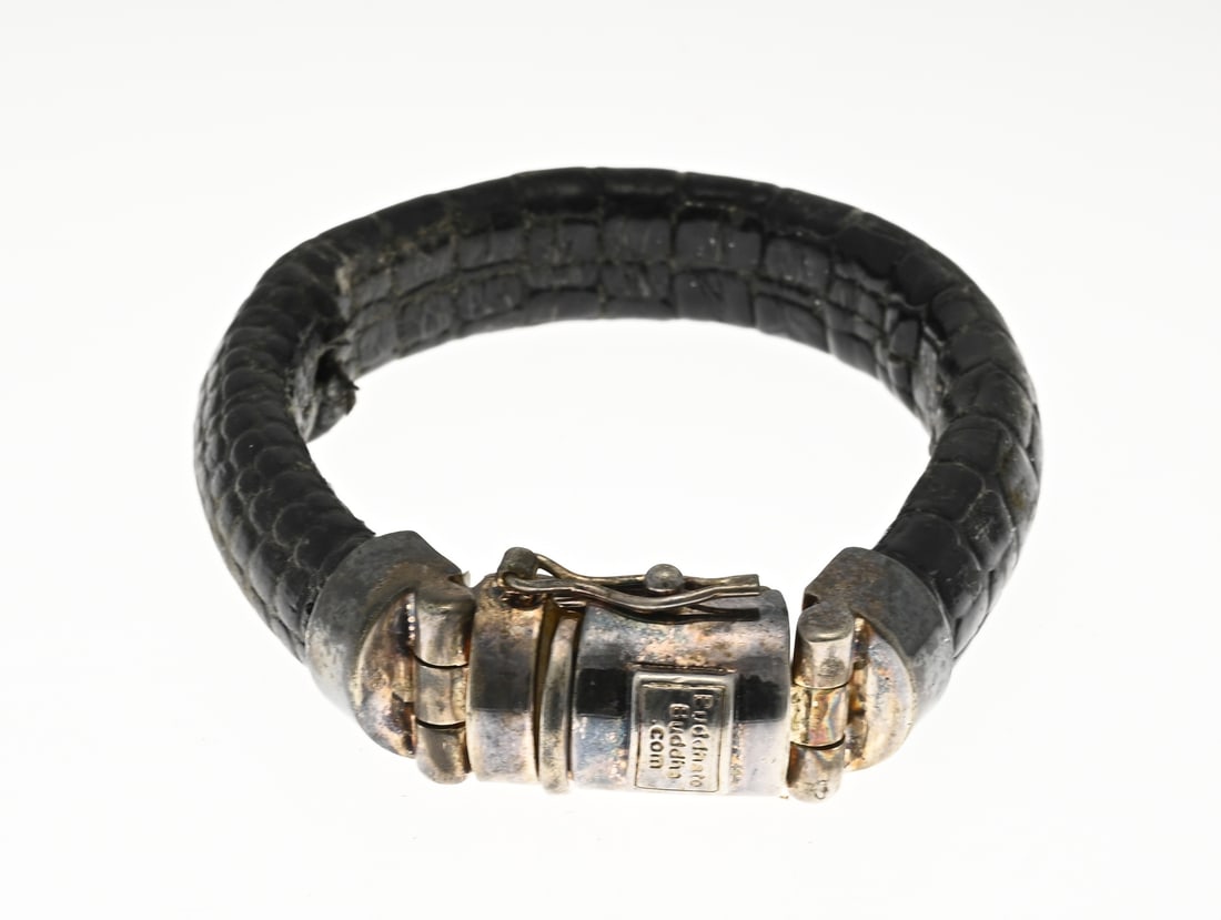 Buddha bracelet with leather strap: Buddha-to-Buddha bracelet, made of textured black leather, with a silver clasp, 925/000. Length 19.5 cm. Width 14 mm. Leather slightly loose on the inside. Otherwise in good condition.