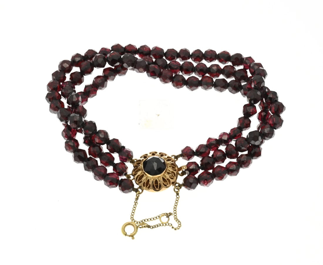 Garnet bracelet with gold: Bracelet with 3 rows of faceted garnet beads, ø 5.5 mm, attached to a yellow gold clasp, 585/000, openwork floral shape with a garnet in the center. With a double safety chain. Length 19 cm. Tota