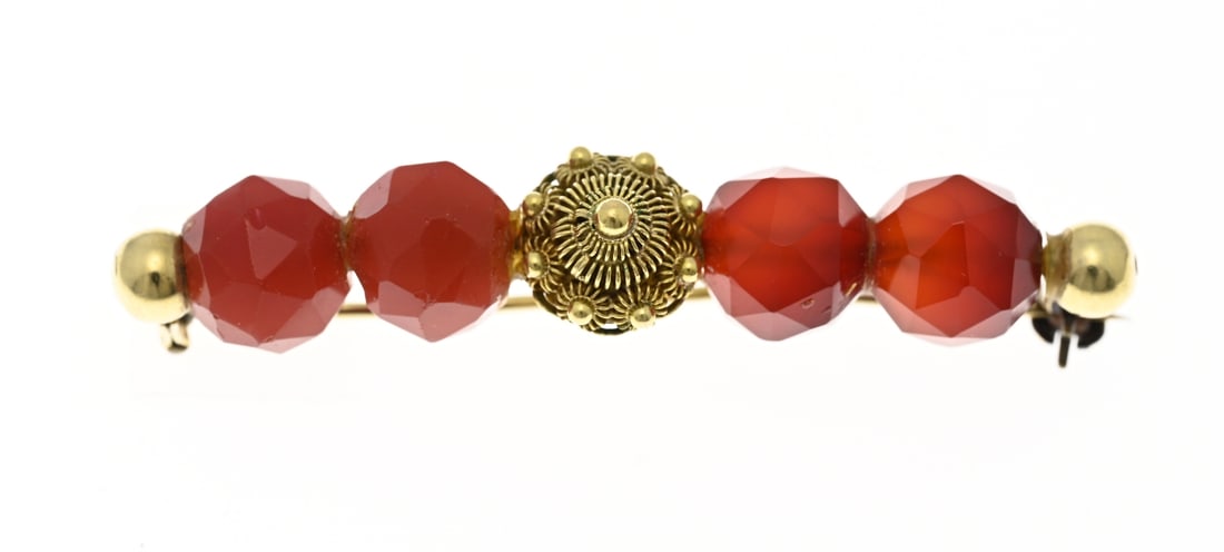 Gold brooch with carnelian: Yellow gold brooch, 585/000, with carnelians. Bar brooch with a yellow gold Zeeland button in the center and 2 round faceted carnelians on either side. ø9.5mm. 10x53mm. approx. 7.6 grams. In
