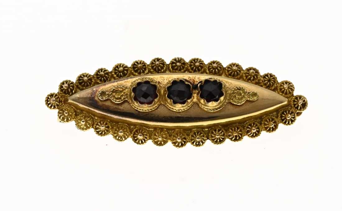Gold marquise brooch with garnet: Yellow gold regional brooch, 585/000, with garnets. Marquise-shaped brooch decorated with buttons and set with 3 faceted garnets. 40x14mm. Approx. 4.0 grams. In good condition.