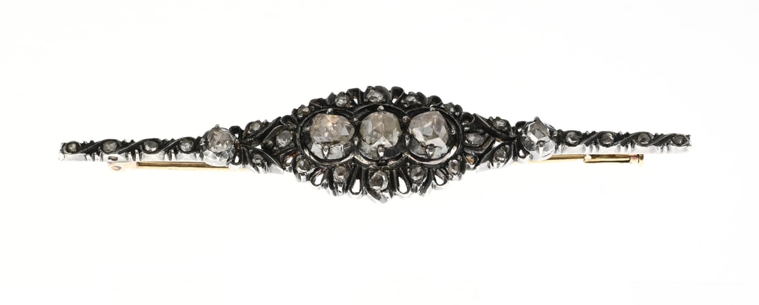 Antique brooch with old diamond: Exceptional antique brooch, gold and silver, with old diamonds. Bar brooch with a contoured silver head richly decorated with old-cut diamonds. In the center of the brooch are three larger rose-cut
