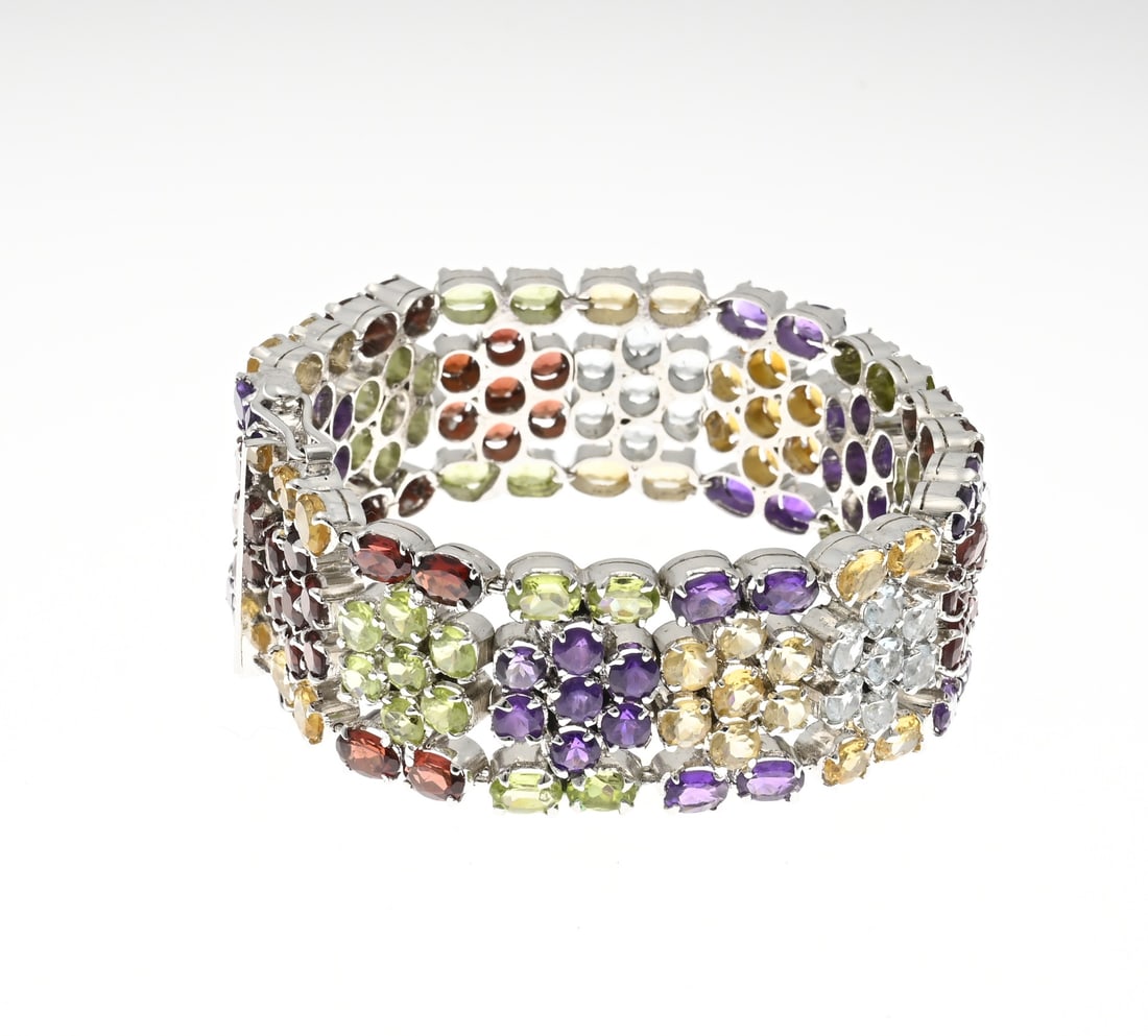 Wide silver bracelet, colored cubic zirconia: Wide silver bracelet, 925/000, with colored cubic zirconia. Bracelet fully set with colored cubic zirconia rosettes. Fitted with a box clasp. Length 19 cm. Width 23 mm. Approx. 62 grams. In very good 