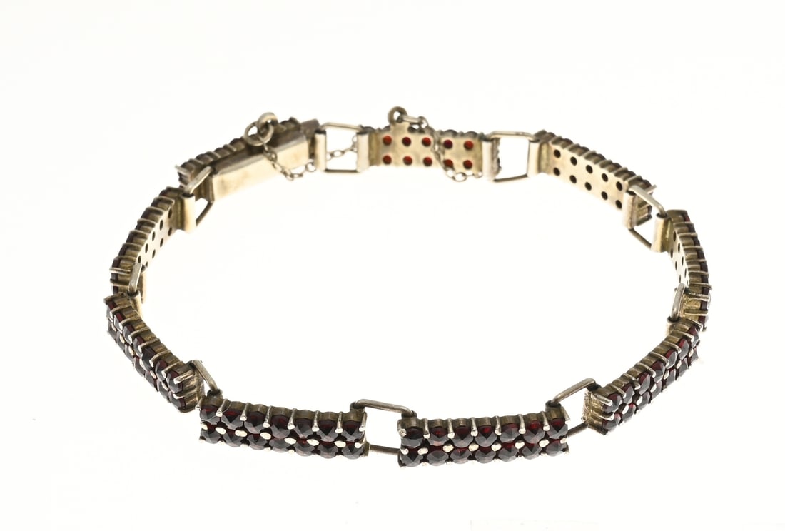 Bracelet with garnet: Gold on silver bracelet with garnets. Bracelet with rectangular links set with 14 garnets. Fitted with a box clasp and safety catch. Width 6 mm, length 17 cm, approx. 10.9 grams. In good condition.