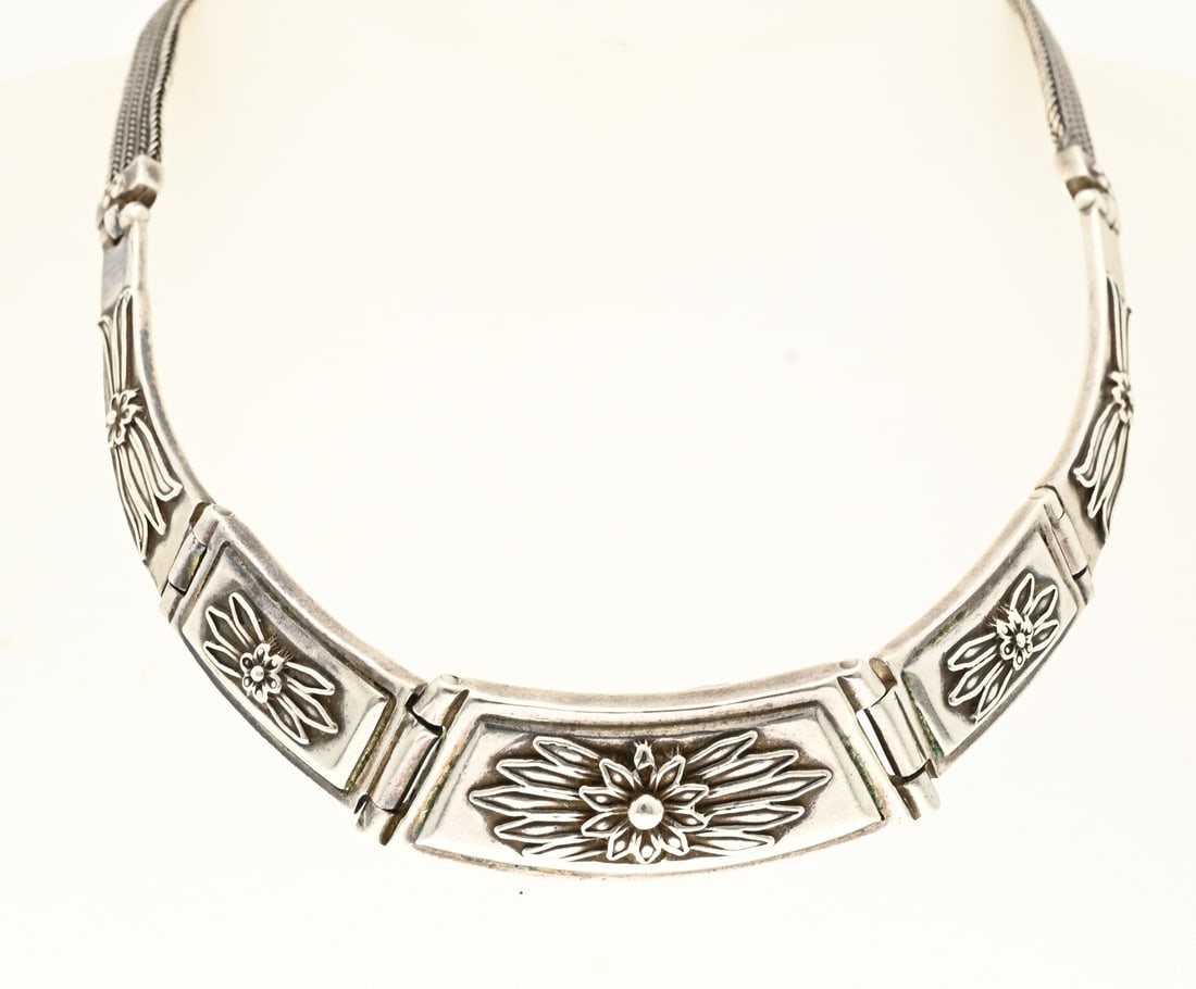 Silver choker: Beautiful silver choker, 925/000, with a braided chain featuring 5 hinged elements, one of which has a floral shape. Gradually increasing in width. The end pieces of the necklace feature floral
