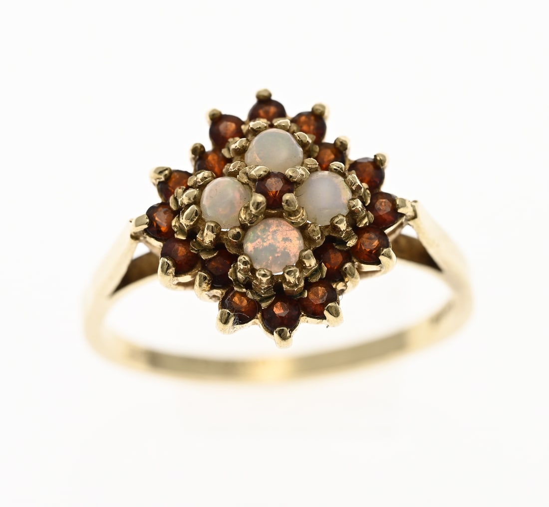 Gold ring with opal and garnet, 9 carat: Ring, 375/000, with a clover-shaped head, set with 4 cabochon-cut white opal stones and surrounded by a rim of garnet stones. Head diameter 14 mm. Diameter 59. Approx. 3.3 grams. In very good conditio
