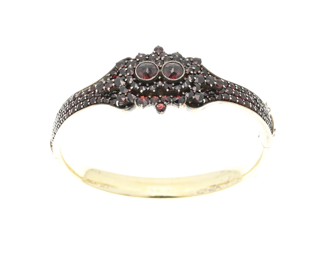 Bangle with grenade: Gold-plated silver bangle, 835/000 with garnet. Hinged bangle fully set with garnet stones and an elaborate upper section featuring a double rosette with garnets. Width 8x22mm. 56x59mm. Approx. 33.4