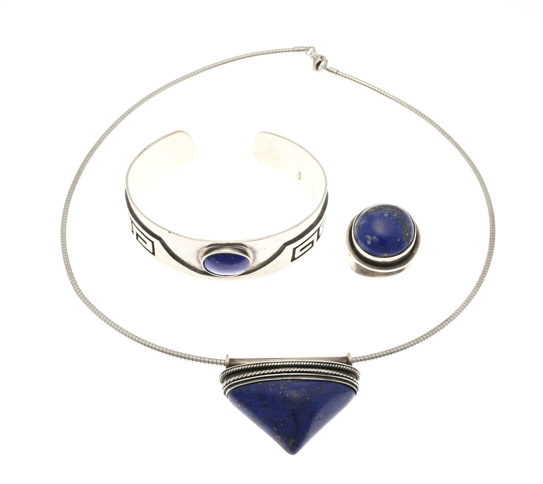 3 Silver jewelry with lapis lazuli: Three pieces of silver jewelry, 925/000, with lapis lazuli: a round necklace with a triangular pendant set with a lapis lazuli, a ring with a round head set with lapis lazuli, and a cuff bracelet,
