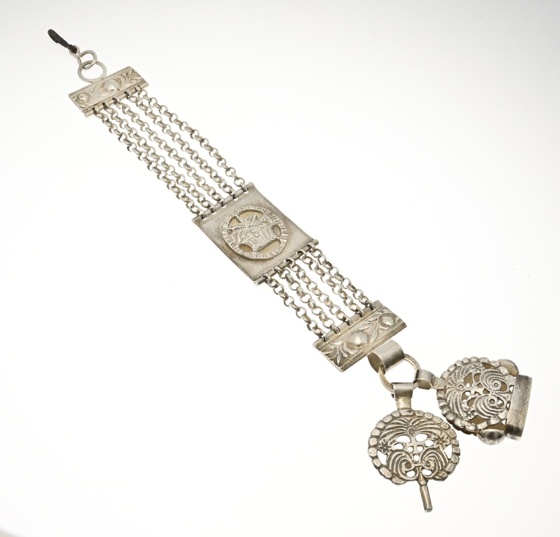 Silver chatelaine with signets: Silver chatelaine with signets, 833/000, with a rectangular element with floral appliqué, 5 rows of jasseron chain. Attached to the chatelaine are a key and a stamp. With metal hook. 32 cm.