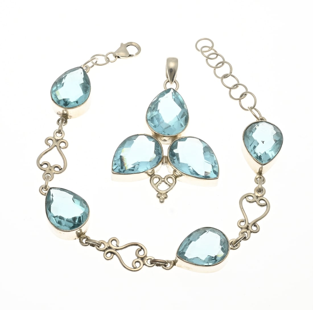 Silver bracelet and pendant with blue stones: Silver bracelet and pendant, 925/000, with light blue stones. Bracelet with coiled links and pear-shaped settings with pear-shaped stones in between. 12 mm. Length 19-23 cm. And a matching pendant