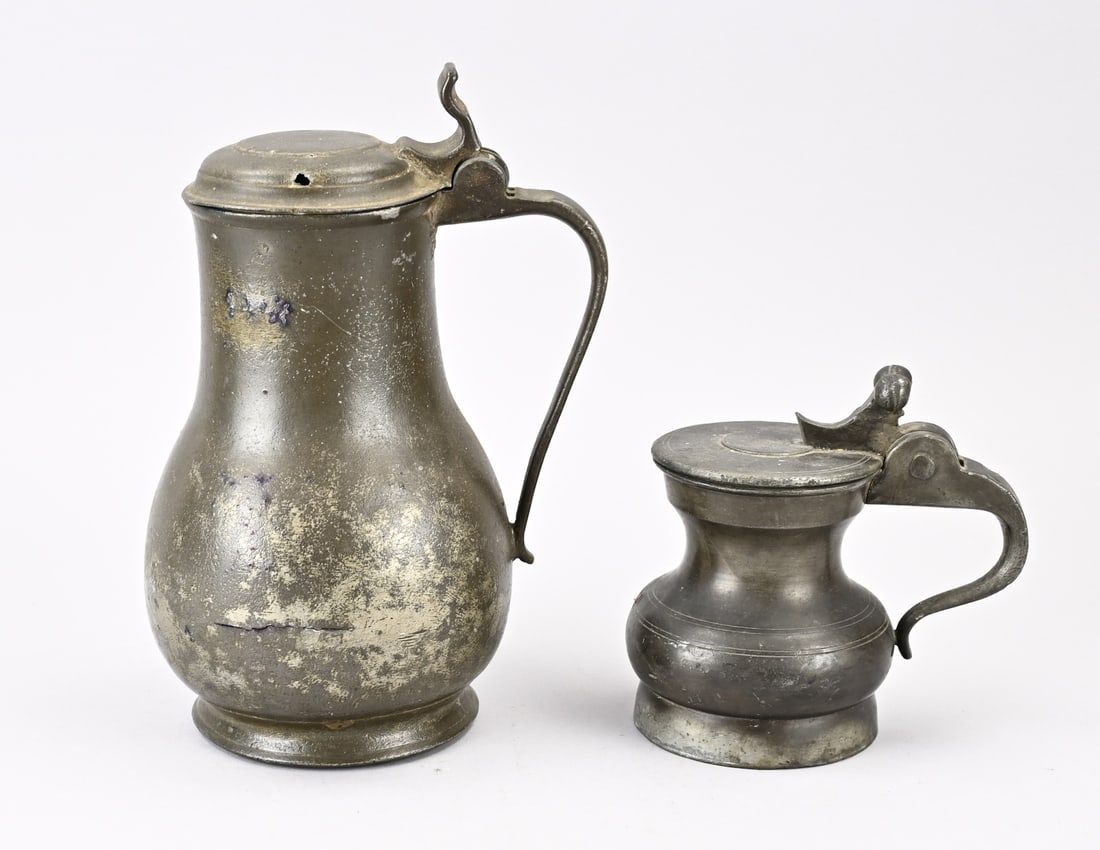2x Antique pewter lidded jug: Two antique pewter lidded jugs. 1x Small, marked with N + crown on lid. 1x Large, possibly 17th century, hairline crack + small hole. Dimensions: 15 - 27 cm. In fair/good condition.