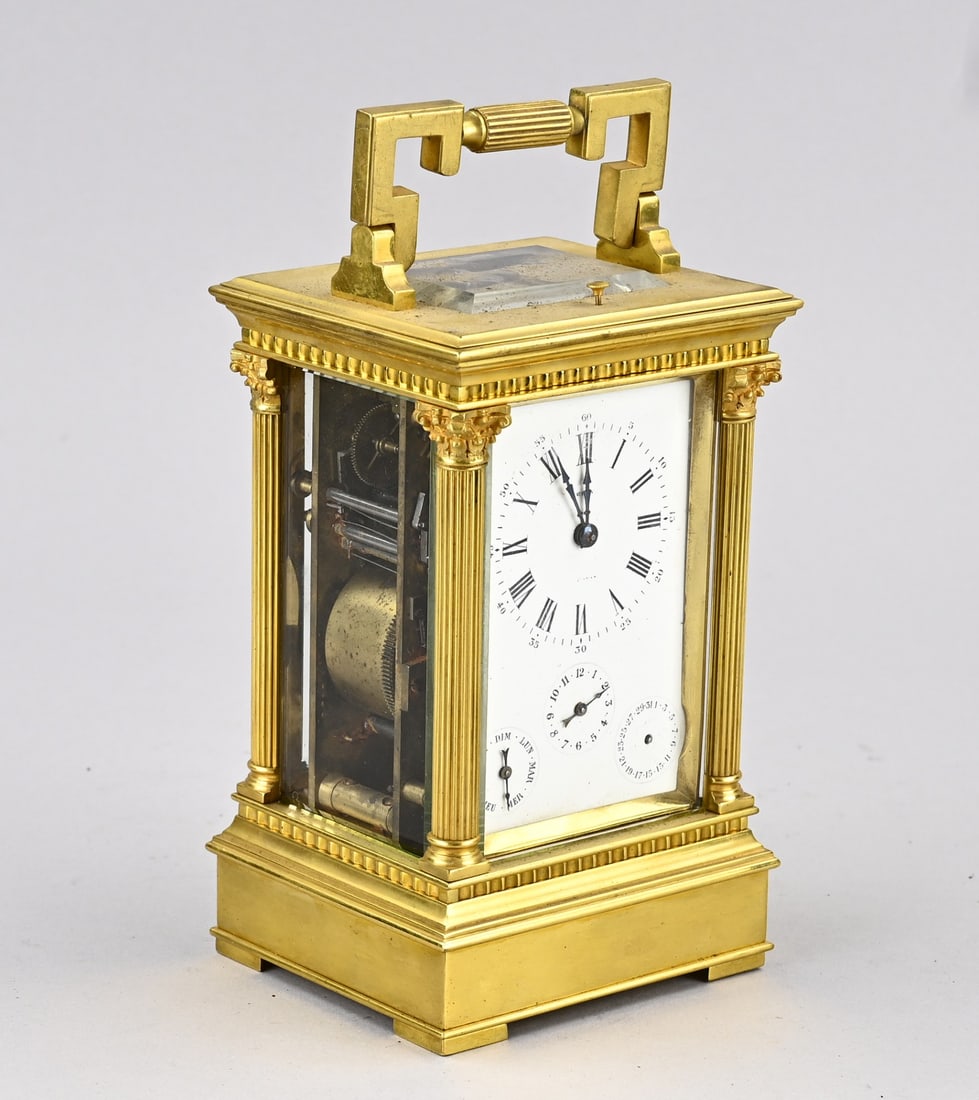 Travel alarm clock with calendar, 1900: Antique gilded brass travel alarm clock with quarter-hour strike, day and date display, with alarm. Petite Sommerie & Grande Sommerie. France. Circa 1900. Dimensions: 21 x 10 x 9 cm. One small hand is