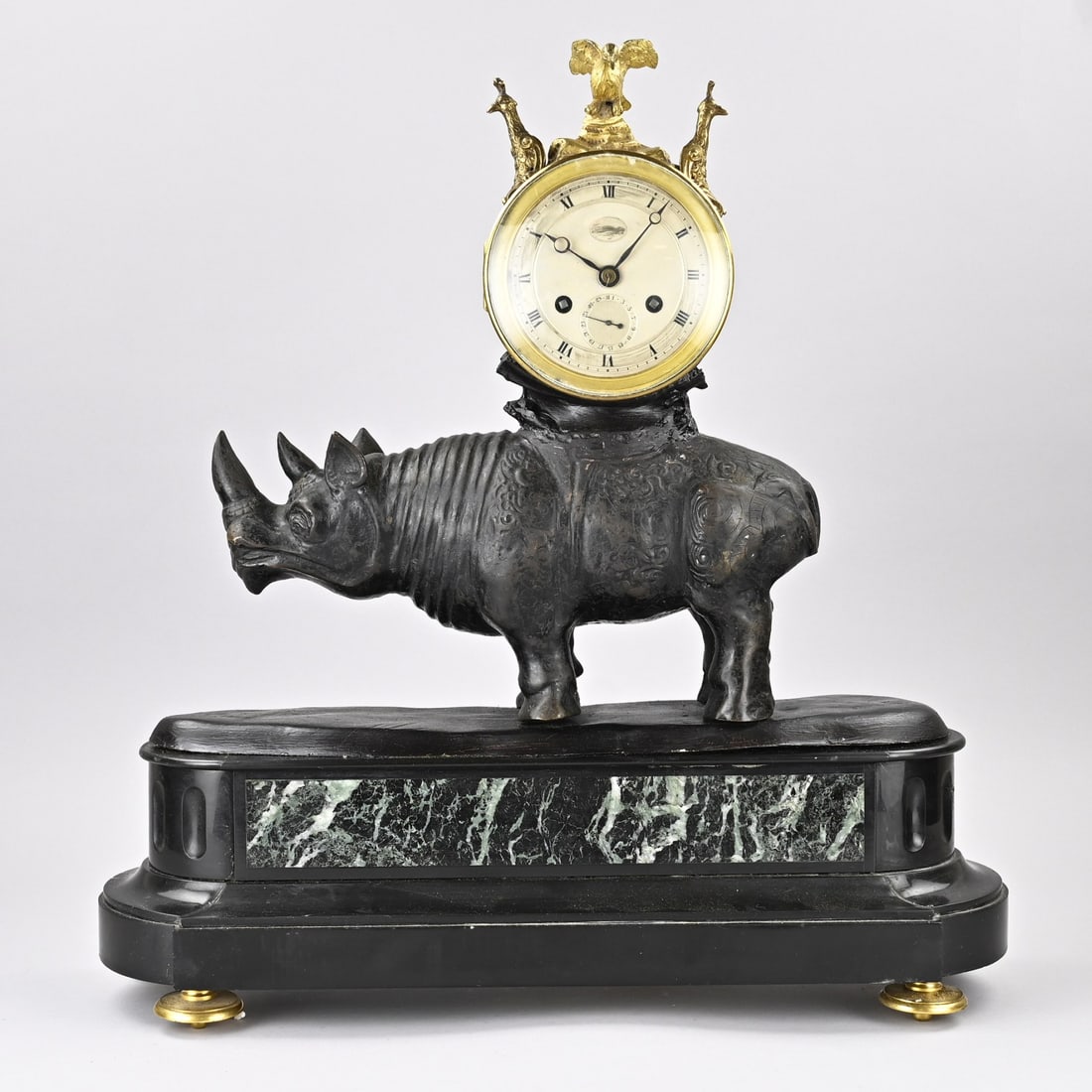 Clock (with rhinoceros): Large antique clock with rhinoceros. Composed of marble and metal. Movement with date display. Dimensions: 54 x 52 x 16 cm. In fair/good condition.