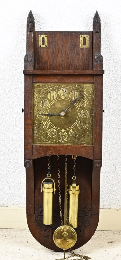 Kobus de Graaff wall clock, 1910: Antique Dutch oak Kobus de Graaff pendulum wall clock with brass dial. 1867 - 1936. Circa 1910. Dimensions: 55 cm. In good condition.